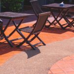 2 wooden coffee table sets on curve beige tile and aggregate cobblestone floor in poolside area